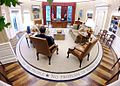 View from fireplace mantel: President Barack Obama from the back sitting near the fireplace with view toward desk, Rose Garden doorway at left, private study door ajar at right, and door to his secretary's office ajar at far left.