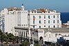 Oblique view of the front of the Great Mosque of Algiers, with a facade consisting of fourteen arches, with a small domed building inside and a large square-towered minaret to the left