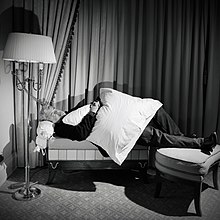 George Lucas lying on a sofa in hotel room with a pillow on his lap.