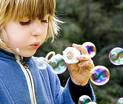 Boy blowing soap bubbles from a bubble ring