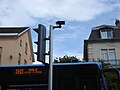 Un bus passant devant un feu tricolore. On retrouve en haut le boîtier et en bas le feu « losange ».