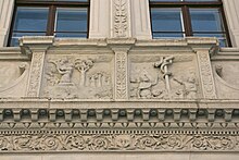 Barevná fotografie s pohledem na pískovcové reliéfy s figurativními motivy na fasádě renesančního domu