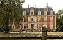 Photographie en couleurs de la façade d'un château en briques et pierres de taille.