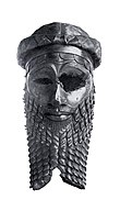Photographie d'une sculpture en métal représentant une tête d'un homme barbue.