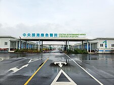 中央援港應急醫院大門，上有藍色中文「中央援港應急醫院」和綠色英文「Central Government-Aided Emergency Hospital」標示。