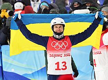 Oleksandr Abramenko portant le drapeau ukrainien et souriant après sa course.