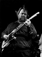 A black and white photo of musician Al Anderson, playing an electric guitar