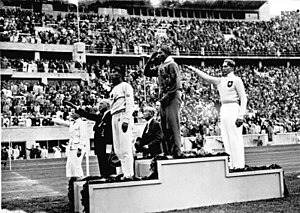 ג'סי אוונס מצדיע לדגל ארצות הברית לאחר שזכה, ב־4 באוגוסט 1936 במדליית הזהב בתחרות הקפיצה לרוחק באולימפיאדת ברלין.