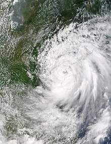 Satellite image of a ragged tropical cyclone, with a loosely defined eye and sprawling rainbands.