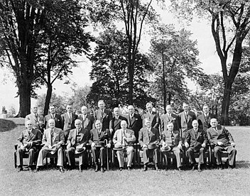 A posed group of men, taken out of doors, with one row seated, one standing