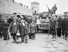 À Mauthausen, prisonniers russes et polonais infirmes après des expérimentations médicales au camp, devant un véhicule de la onzième division blindée de la troisième armée américaine qui a libéré le camp.