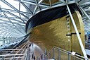 ☎∈ The restored stern (with stern draft and rudder) of the Cutty Sark elevated 3 metres above its dry-dock under its glass-roofed visitors' centre in June 2012.