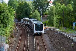 oversiktsbilde over tre T-banespor. Et tog er synlig på det midterste, og kjører fra seeren, ut av bildet