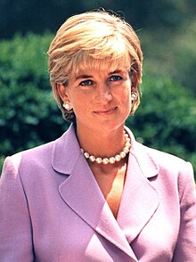 Diana wears a pink skirt suit and a pearl necklace.