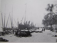 Bateau à quai entouré de marchandises avec personnages