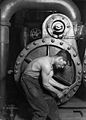 Image 41Lewis Hine's 1920 image "Power house mechanic working on steam pump," which shows a working class young American man with wrench in hand, hunched over, surrounded by the machinery that defines his work.