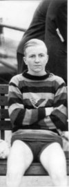 George Burleigh, sitting on a bench wearing his swimming trunks and a striped sweater.