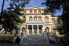 Photographie d'un bâtiment néoclassique situé en haut d'un grand escalier blanc.