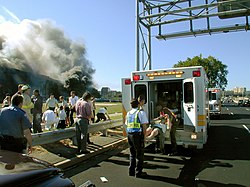 An injured victim is being loaded into a paramedic van with the burning Pentagon in the background