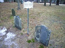 Two gravestones partly covered with moss and a small sign which reads "John Alden Burial Place"