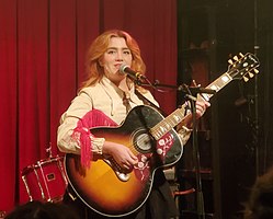 CMAT onstage holding an acoustic guitar