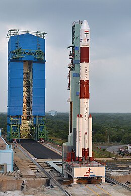 Red and white rocket stands on the launch pad