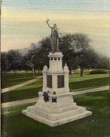 A monument with a woman at the top of a marble pedestal.