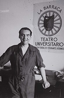 Federico García Lorca smiling, standing in front of a theatre poster