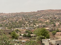 A town with a variety of brick buildings and structures. Green trees stick out against the reddish/orange landscape.