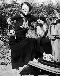 Bonnie Parker szivarral és pisztollyal az 587 956 texasi rendszámú Ford V-8 sedan automobiljuk előtt 1933-ban