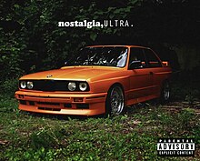 An orange BMW E30 M3 in plain sight amidst lush greenery.