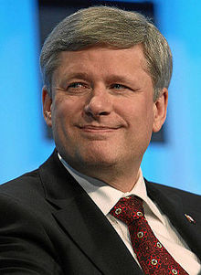 Photograph of Harper in 2010 wearing a dark suit, red tie, and a Canadian flag lapel pin.