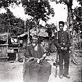 Image 10Temne leader Bai Bureh seen here in 1898 after his surrender, sitting relaxed in his traditional dress with a handkerchief in his hands, while a Sierra Leonean West African Frontier Force soldier stands guard next to him (from Sierra Leone)