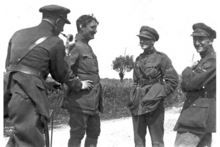 Photographie noir et blanc de quatre hommes, en uniforme, discutant.