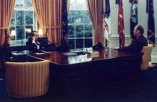 Nixon seated behind the Wilson desk and Ford seated next to it.