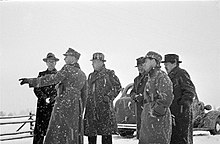 A group of foreign journalists observing something during snowfall in Mainila, where a border incident between Finland and the Soviet Union escalated into the Winter War.