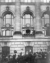 Scheidemann ruft vom Westbalkon (zweites Fenster nördlich des Portikus) des Reichstagsgebäudes die Republik aus.