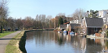 photo d'un canal bordé d'une route à gauche et de maisons à droite