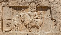 Relevo rochoso em Naqsh-e Rustam; o imperador persa sassânida Shapur I (a cavalo) com imperadores romanos submetendo-se a ele