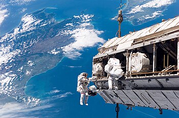 Letoví specialisté mise STS-116, Američan Robert Curbeam (vlevo) a Švéd Christer Fuglesang z ESA, při výstupu do vesmíru nad Cookovým průlivem mezi Jižním (vlevo) a Severním ostrovem Nového Zélandu