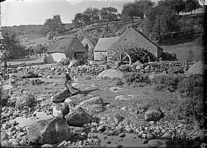 Femme avec son enfant assise près du moulin du Pont.