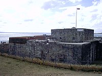 Et lavt, gråt slot af sten ved bredden af havet