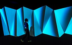 Person går framför projektioner i utställning
