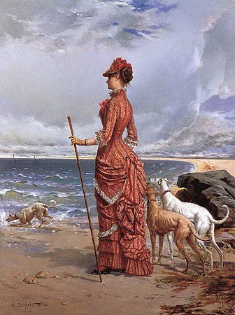 Signora sulla spiaggia con i levrieri
