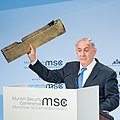 رئيس الوزراء الإسرائيلي بنيامين نتنياهو متفاخرًا بعرض قطعة في مؤتمر ميونخ للأمن 2018، من طائرة إيرانية أسقطتها إسرائيل، بعد أن اعترضَت الأجواء الإسرائيلية.