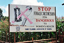 Roadside billboard saying "Stop female circumcision. It's dangerous to Women's health. Family Planning Association of Uganda." Displaying a crossed out razorblade and knife on the left.
