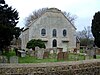 A white building in a graveyard with a flat-topped gable