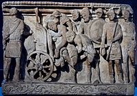 Menelaus and Meriones lifting Patroclus' corpse on a cart while Odysseus looks on; alabaster urn, Etruscan artwork from Volterra, 2nd century BC