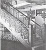 Staircase in a marble hallway, with ornate decorative metalwork and light fixtures