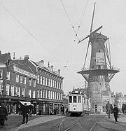 voie de tramway bordée de maisons et d'un moulin à vent